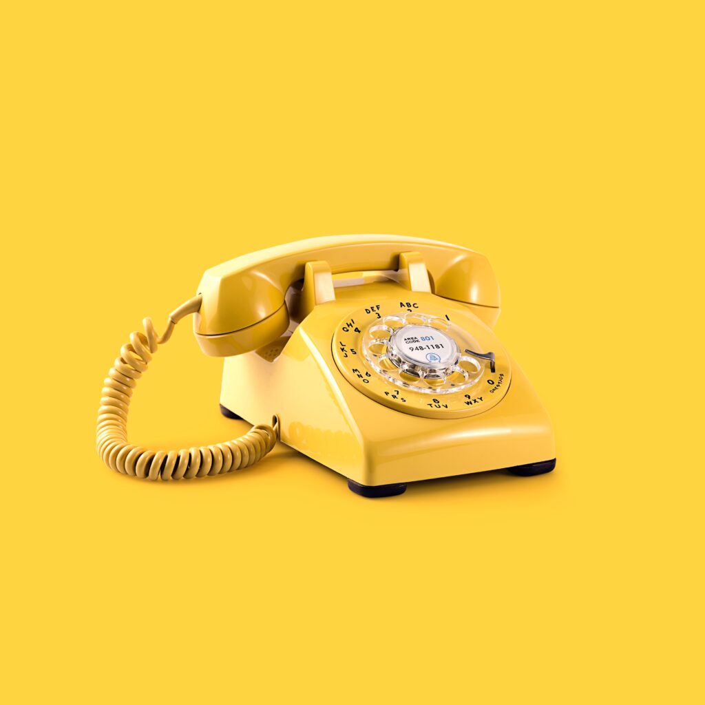 Classic yellow rotary phone on a matching background for a vintage look.