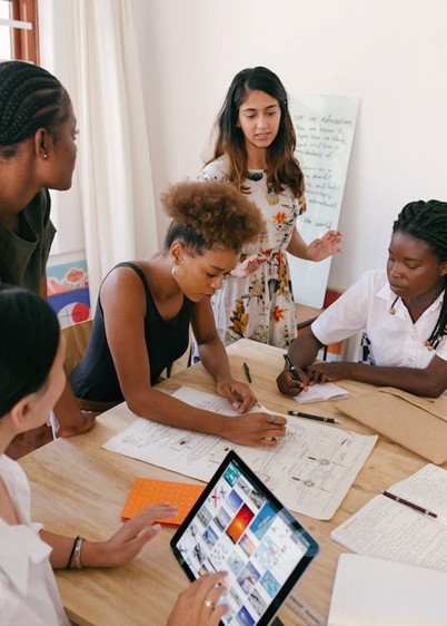 Group of women collaborating at a table with papers and a tablet.